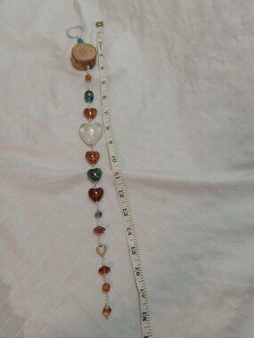 Handmade hanging decoration featuring handcrafted glass beads on a wooden base